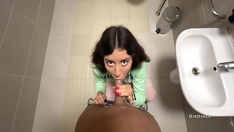 Brunette in red shorts gets a handjob in a public toilet